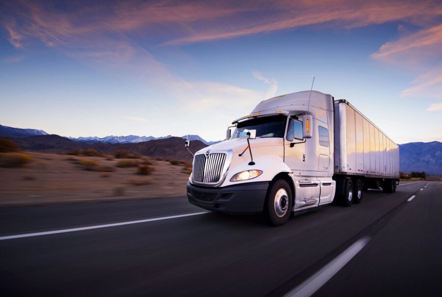 White truck with trailer driving on the highway